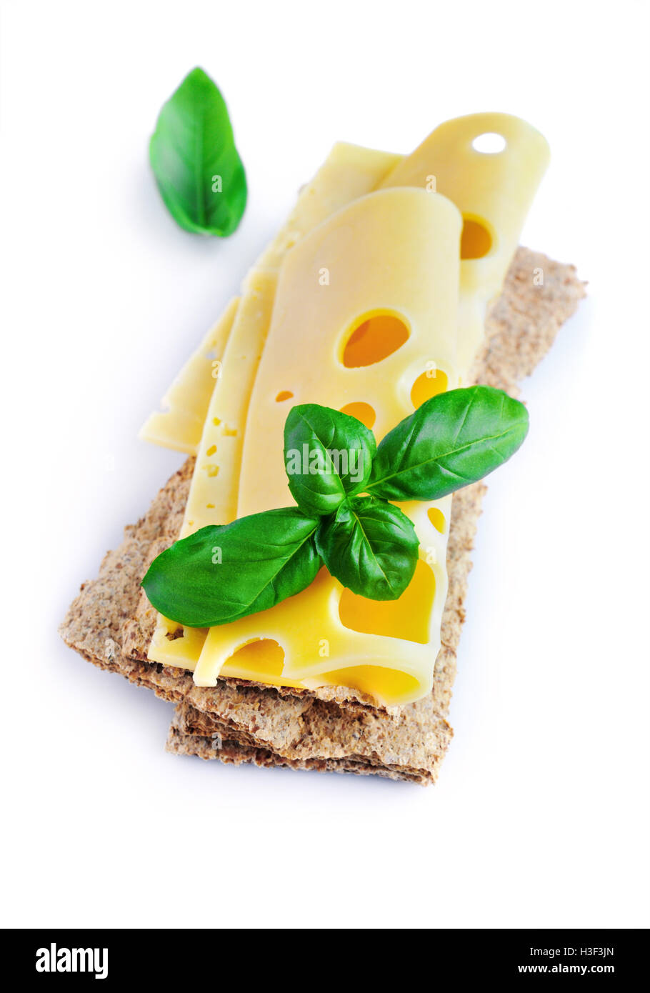 Maasdam tranches de fromage sur pain croustillant avec le basilic isolé sur fond blanc Banque D'Images