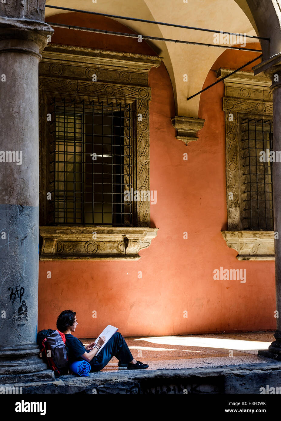 Un étudiant de vous détendre sur la chaussée sous portique à Bologne, Italie Banque D'Images