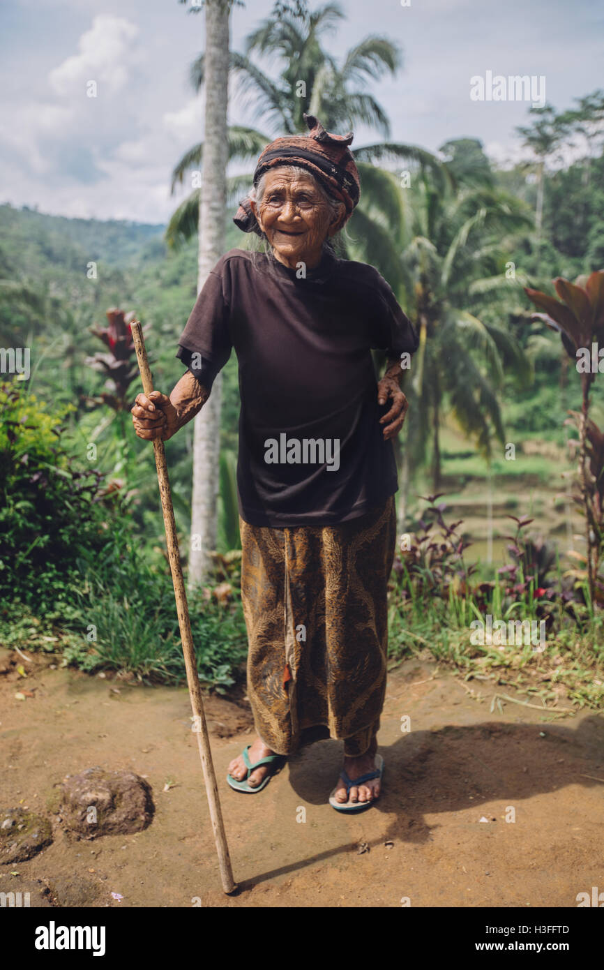 Full Length portrait of smiling vieille femme debout avec un bâton. Femme senior à l'extérieur dans la campagne. Banque D'Images