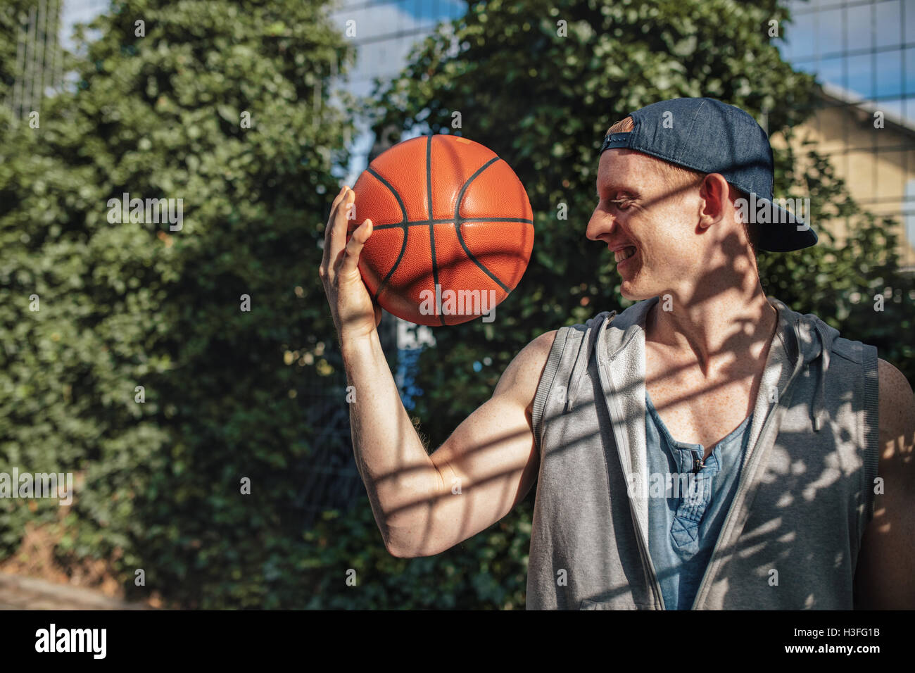 Portrait de jeune homme face à la Basket-ball à dans la main. Teenage guy tenant une balle sur une cour. Banque D'Images