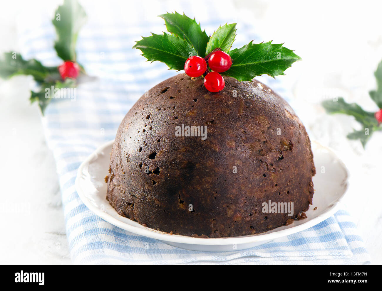 Le pudding de Noël avec de houx sur une plaque blanche. Selective focus Banque D'Images