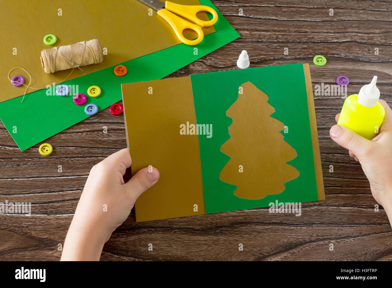 L'enfant de créer des cartes de vœux de noël sapin de fête en papier. Le papier colle enfant détails. Projet d'art pour enfants, la couture, c Banque D'Images