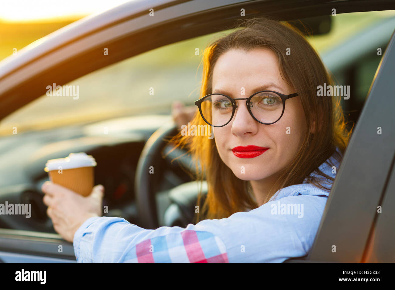 Belle jeune femme avec du café pour aller conduire sa voiture Banque D'Images