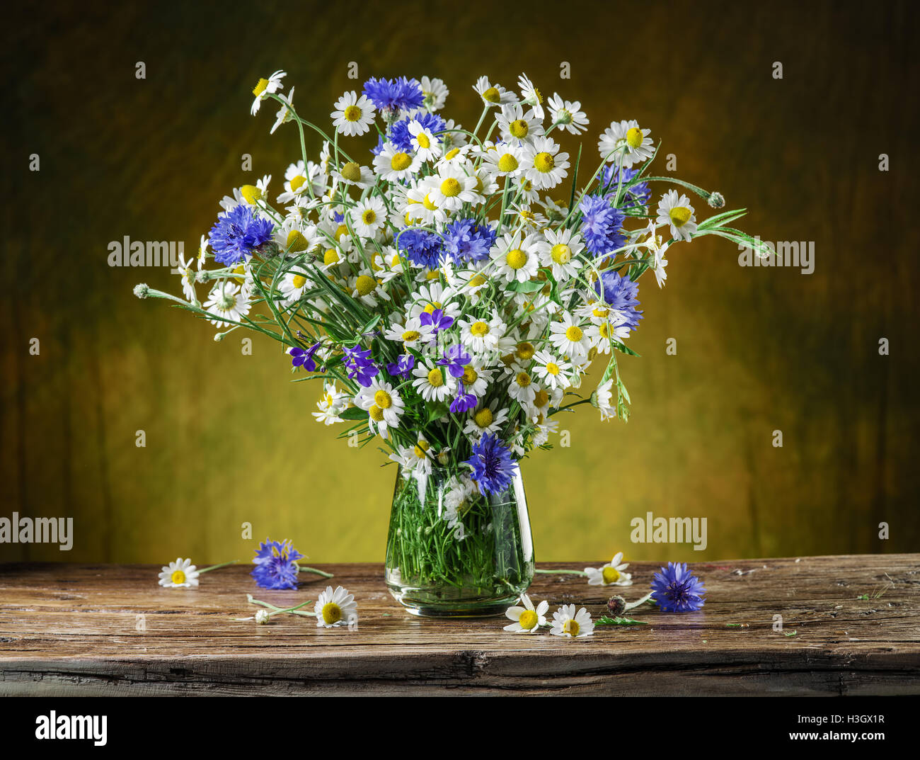 Bouquet de camomille et barbeaux dans le vase sur la table en bois. Banque D'Images