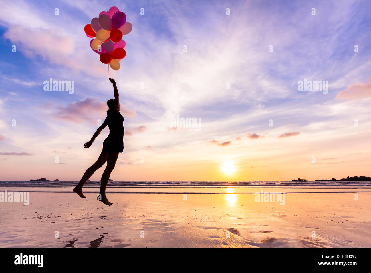 Femme dans un rêve heureux volant dans le ciel levé par ballons d'hélium Banque D'Images