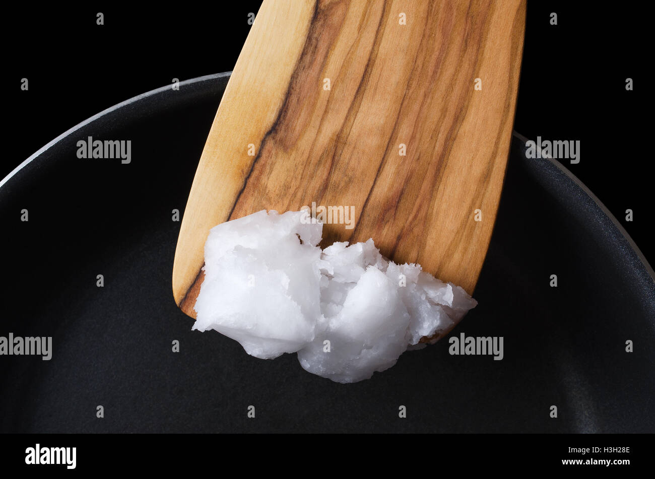 L'huile de noix de coco sur la spatule en bois plus de pan en téflon. L'huile de coprah, également une huile comestible, extraite de l'amande de coco de la viande. Banque D'Images