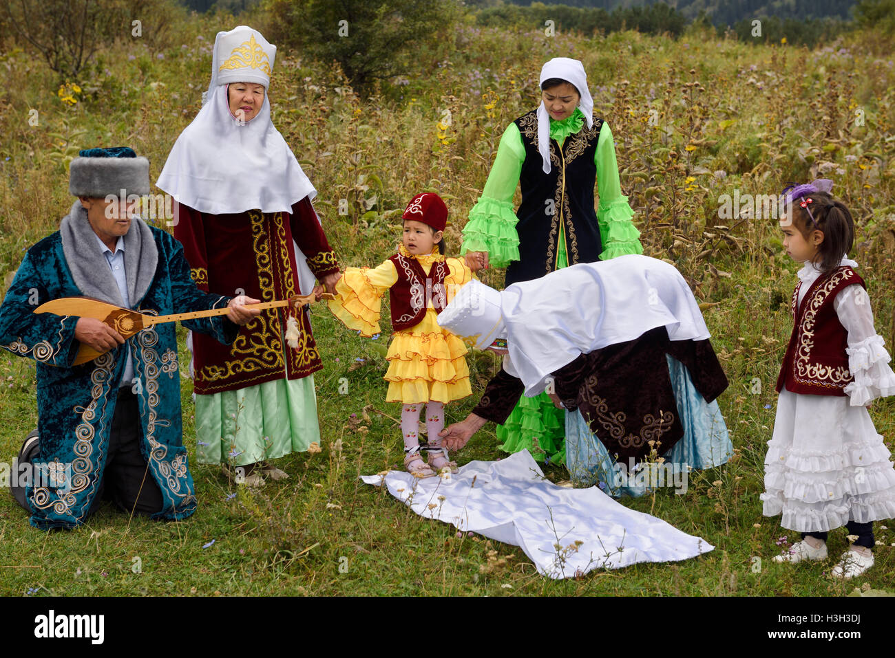 Kesu tusau couper le bout des pieds de l'enfant avec des ciseaux traditionnel kazakh cérémonie familiale avec jeune fille au Kazakhstan Banque D'Images