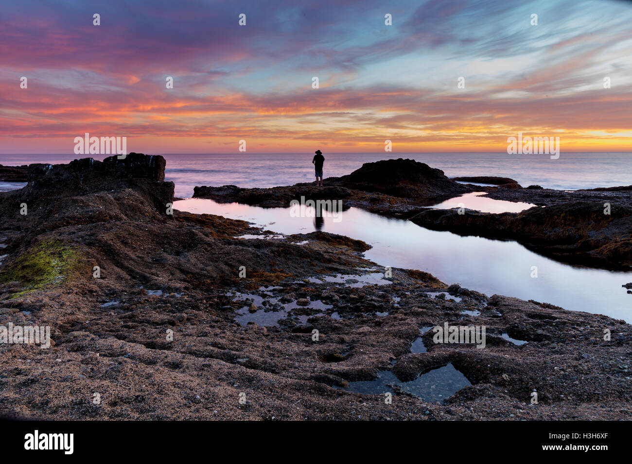 Homme seul sur les rochers au coucher du soleil au Treasure Island Beach à Laguna Beach, California, United States Banque D'Images