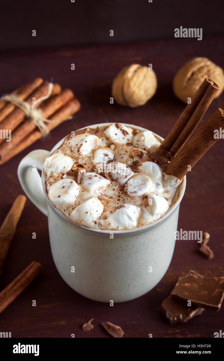 Boire un chocolat chaud avec des guimauves, chocolat et cannelle sur fond de bois rustique - maison verre pour wi Banque D'Images
