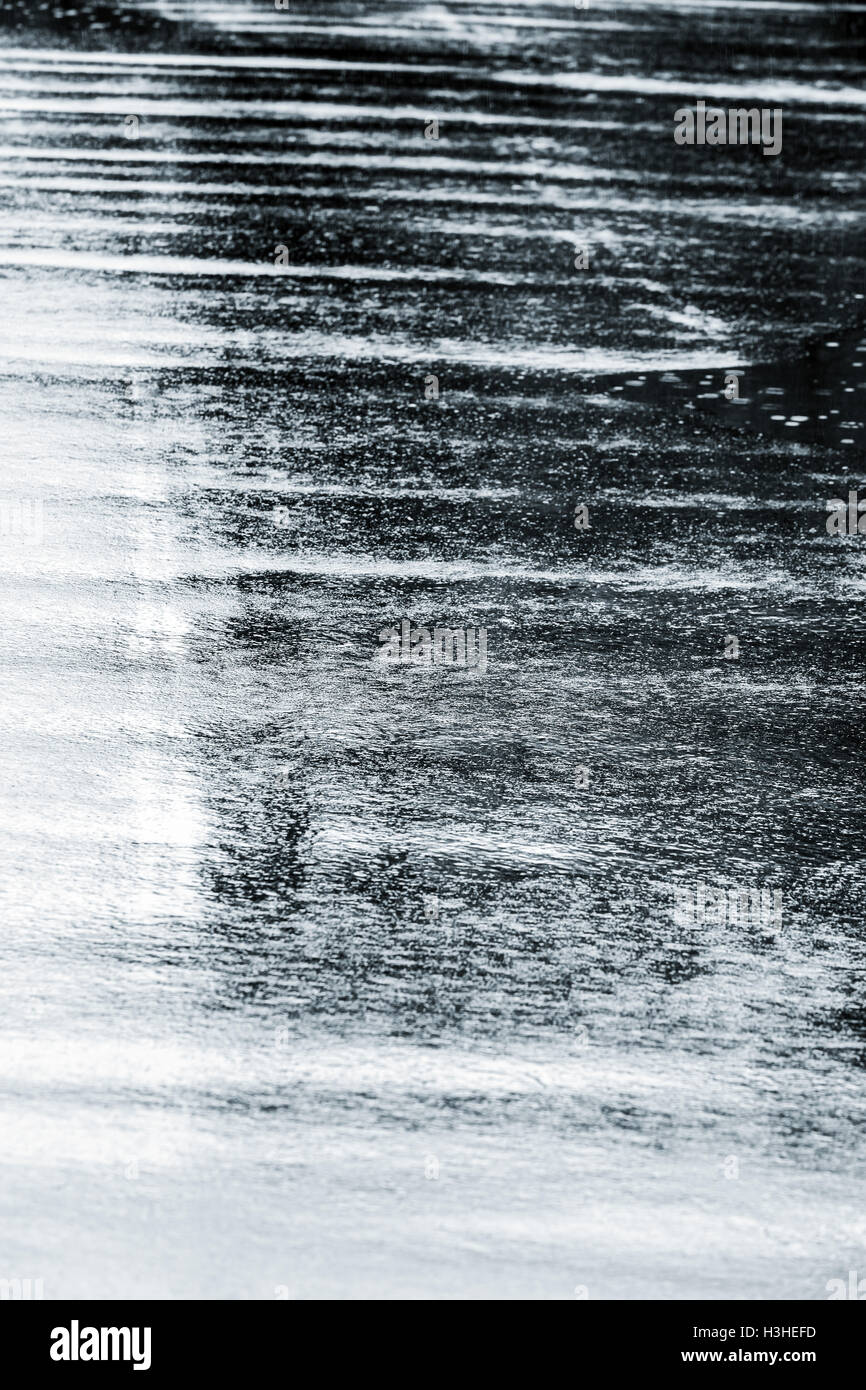 Arrière-plan avec des gouttes de pluie sur la chaussée après une averse les éclaboussures Banque D'Images