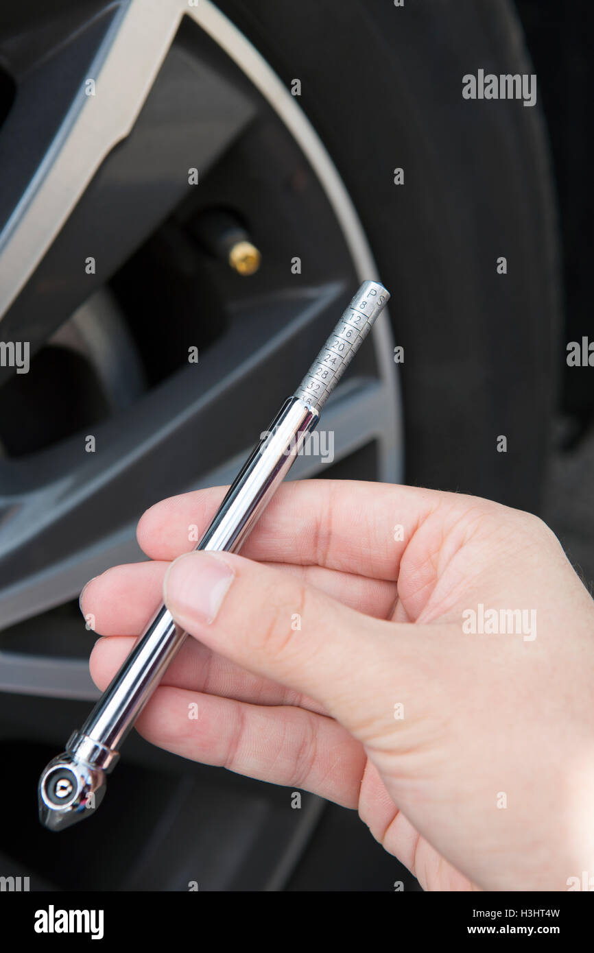 Close Up de contrôle de pression des pneus de voiture à l'aide d'un manomètre Banque D'Images
