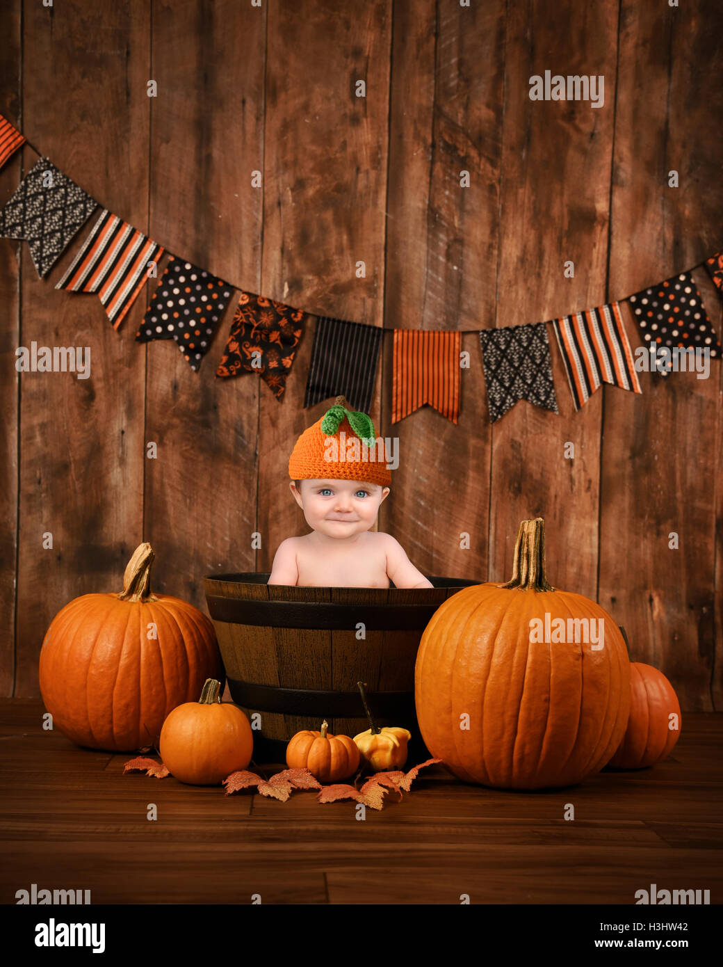 Un peu mignon bébé est assis dans un panier de bois avec automne halloween pumpkins autour de l'enfant pour un message portrait de saison Banque D'Images