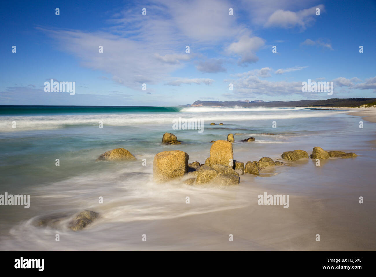 Des vagues dans une mer calme briser contre les rochers sur une plage appelée Friendly plages dans le parc national de Freycinet Banque D'Images