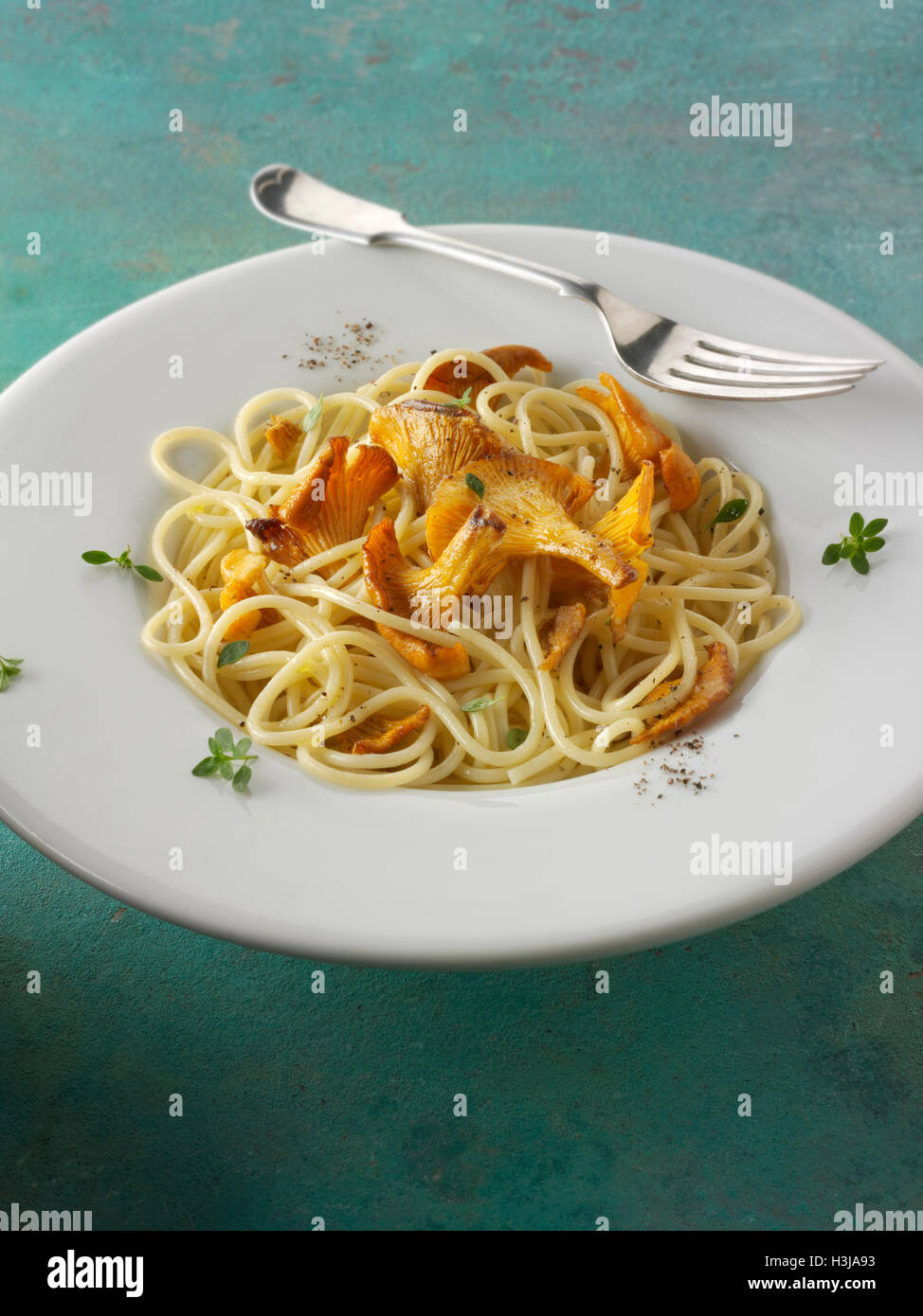 Wiild chanterelle ou girolle organiques Champignons (Cantharellus cibarius) ou sautés au beurre et avec des spaghetti hebs Banque D'Images
