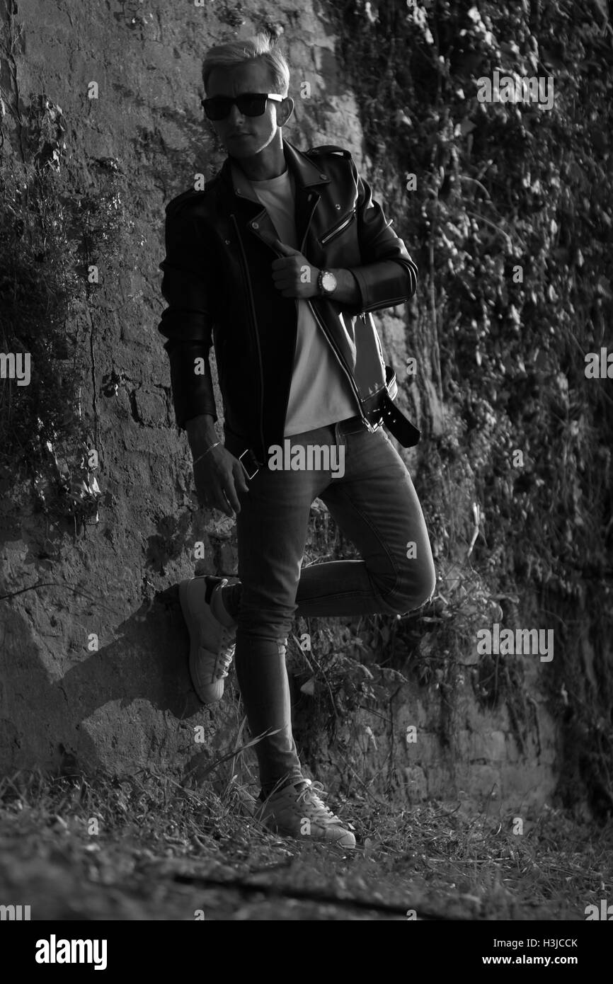 Jeune homme posant en blouson de cuir noir et blanc à la mode cool Banque D'Images