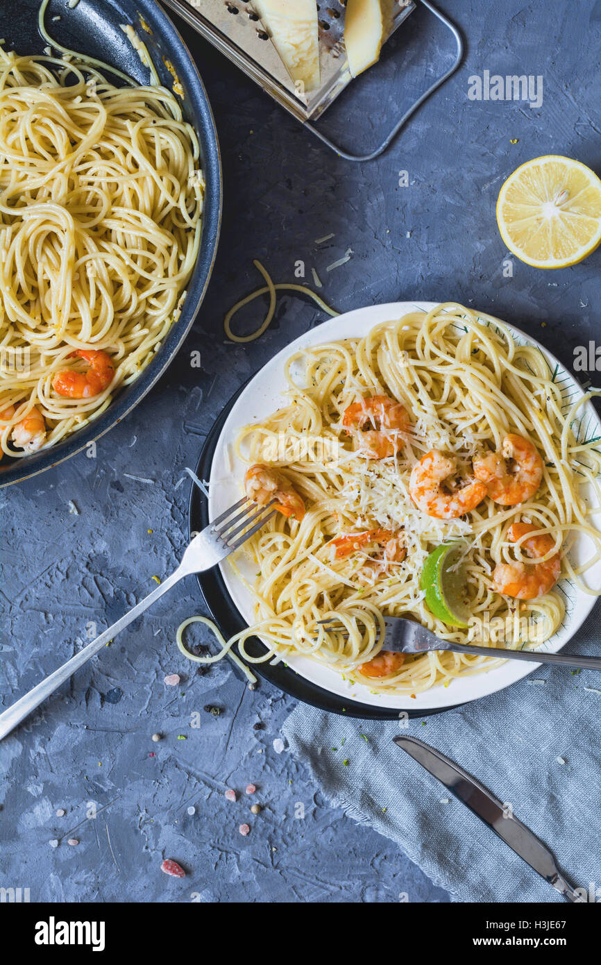 Asta italienne spaghetti aux crevettes et fromage parmigiano reggiano. Vue de dessus, à la verticale. Arrière-plan de béton Banque D'Images