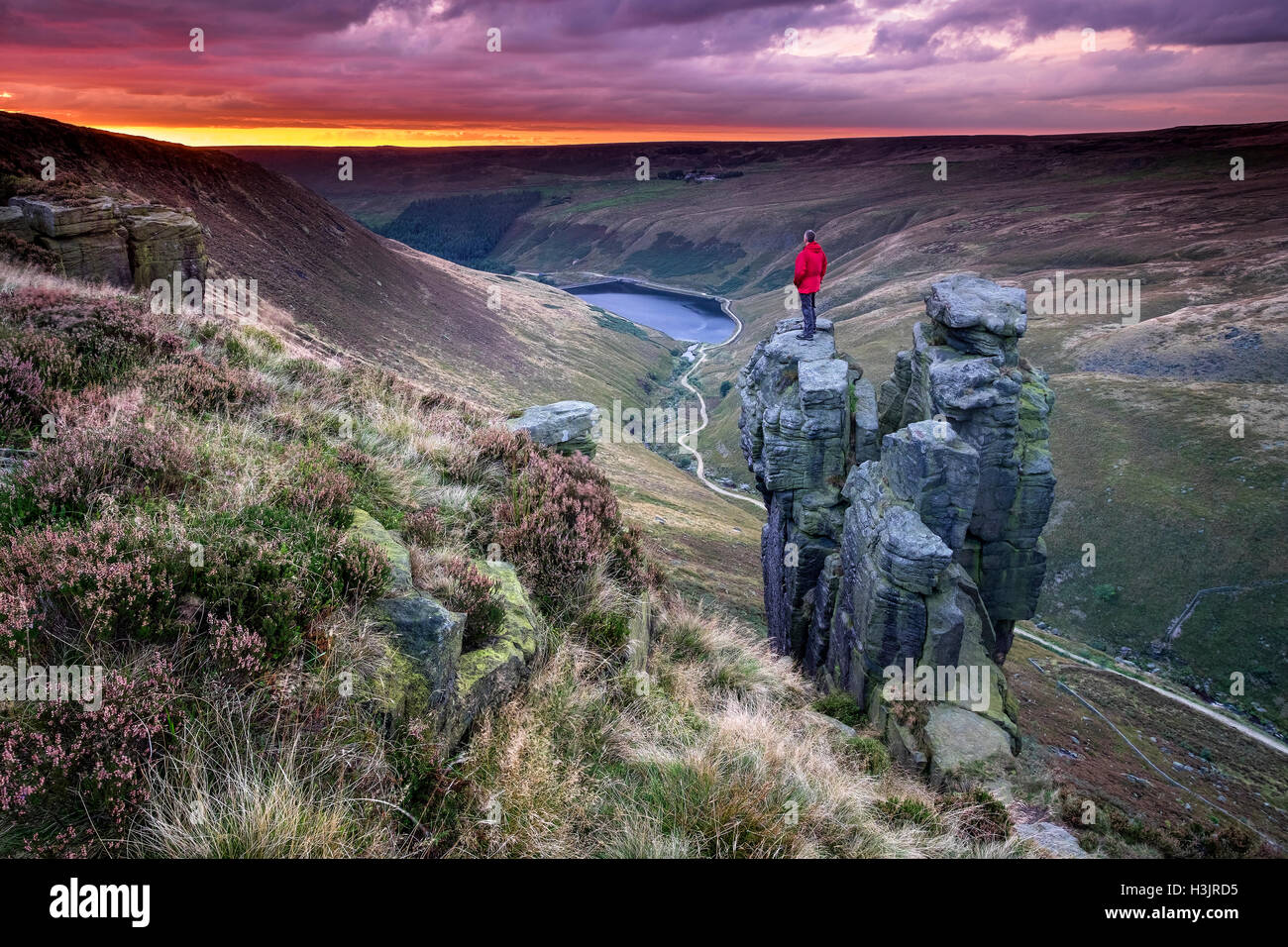 Walker sur le Trinnacle Rock au-dessus du réservoir de Greenfields au coucher du soleil, Tameside Moor, Peak District, Greater Manchester, Angleterre Banque D'Images
