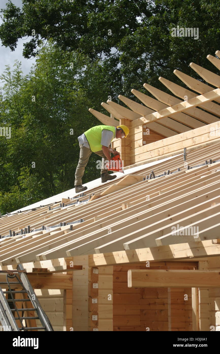 Un travailleur utilise un pistolet à essence pour fixer des plaques pour toiture sur une auto-construction bois maison dans le Kent, UK. En vedette dans le programme TV Grand Designs Banque D'Images