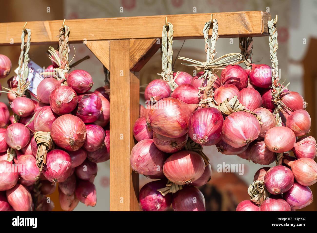 Des tresses d'oignons rouges vendus en Italie dans le marché agricole. Banque D'Images