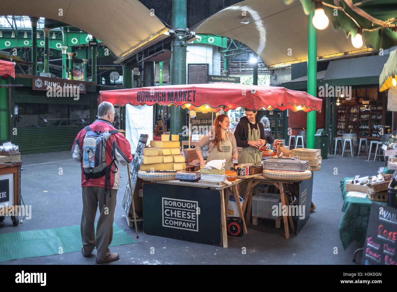 Borough Market, London UK vendeur heureux jeune homme et femme dans un stand fromage servir un client Banque D'Images