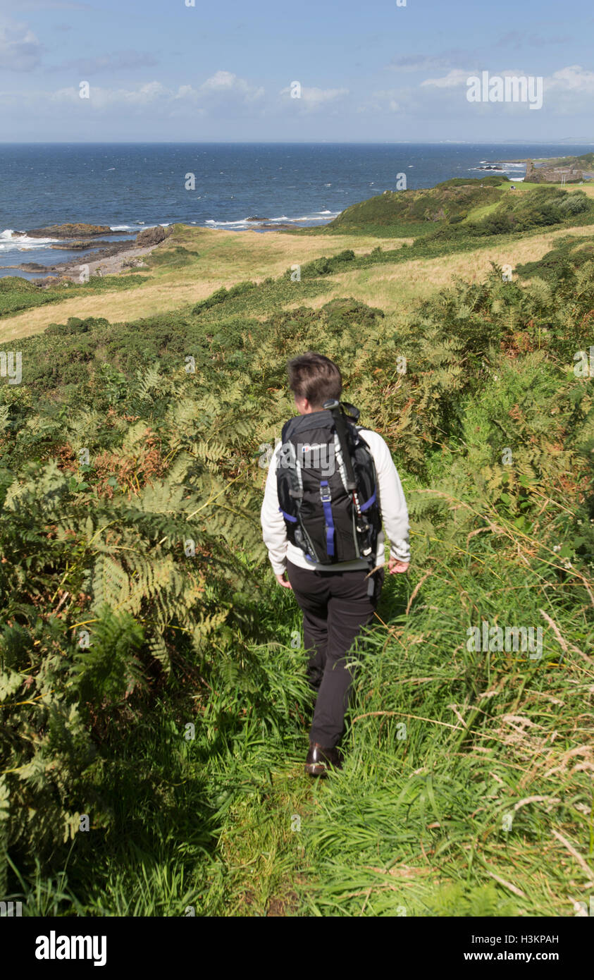 Côte d'Ayrshire, en Écosse. Vue pittoresque d'une dame Walker sur le chemin du littoral de l'Ayrshire, avec Dunure dans l'arrière-plan lointain. Banque D'Images