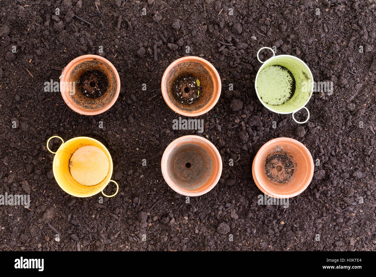 Quatre pots en argile et en métal en deux rangées de trois sur la terre noire riche Banque D'Images