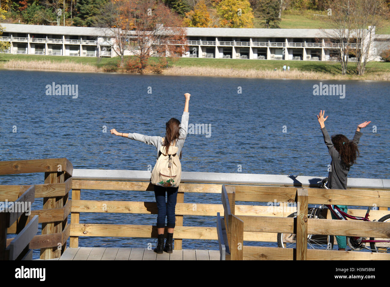 Blue Ridge Parkway, Virginie, États-Unis. Deux enfants sur le pont du lac Abbott en automne, avec des sommets d'Otter Lodge en face. Banque D'Images