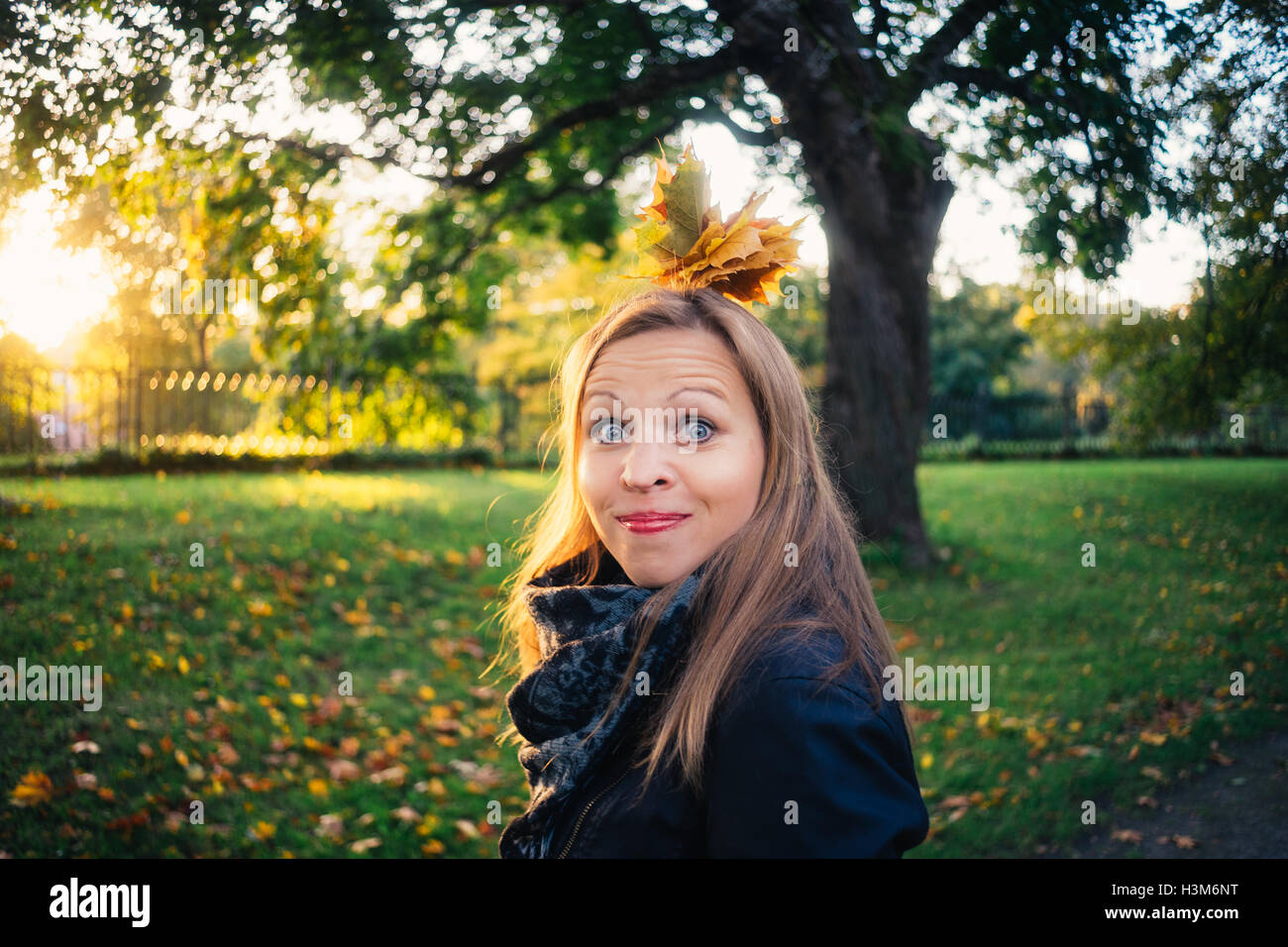 Jeune femme émotionnelle avec bouquet de feuilles faire une grimace en parc d'automne. Concept de l'automne Banque D'Images