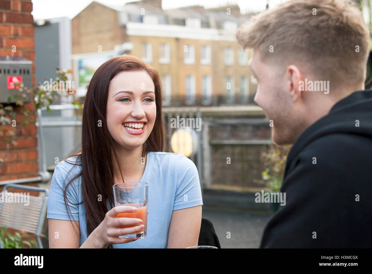 Jeune couple chatting on terrace Banque D'Images