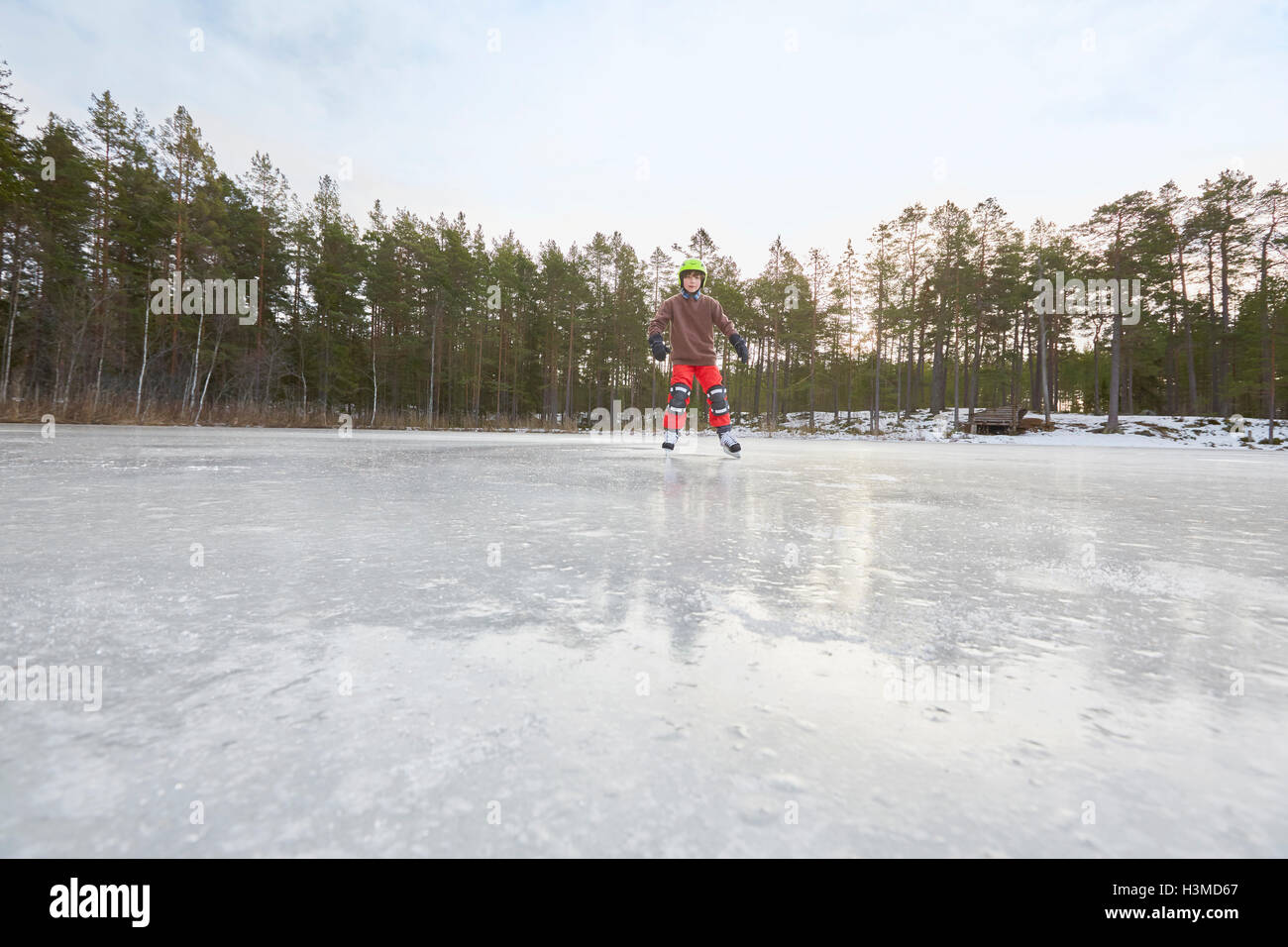 Boy le patin à glace sur un lac gelé, Gavle, Suède Banque D'Images