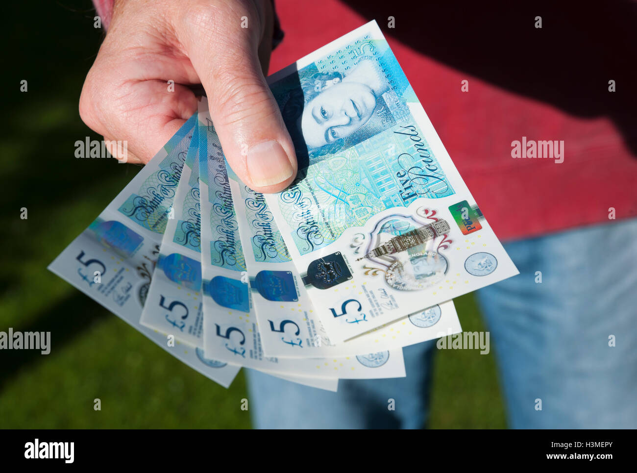 Gros plan de la personne homme détenant £5 billet polymère cinq livres billets monnaie anglaise billets cash England UK Royaume-Uni GB Grande-Bretagne Banque D'Images