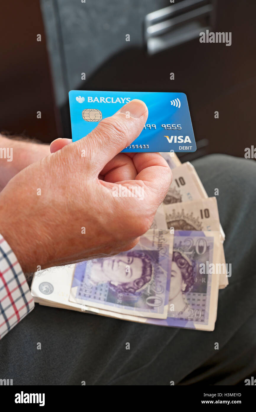 Gros plan de la personne homme détenant visa carte bancaire de débit et vingt livres billets argent anglais billets de banque England UK Royaume-Uni GB Grande-Bretagne Banque D'Images
