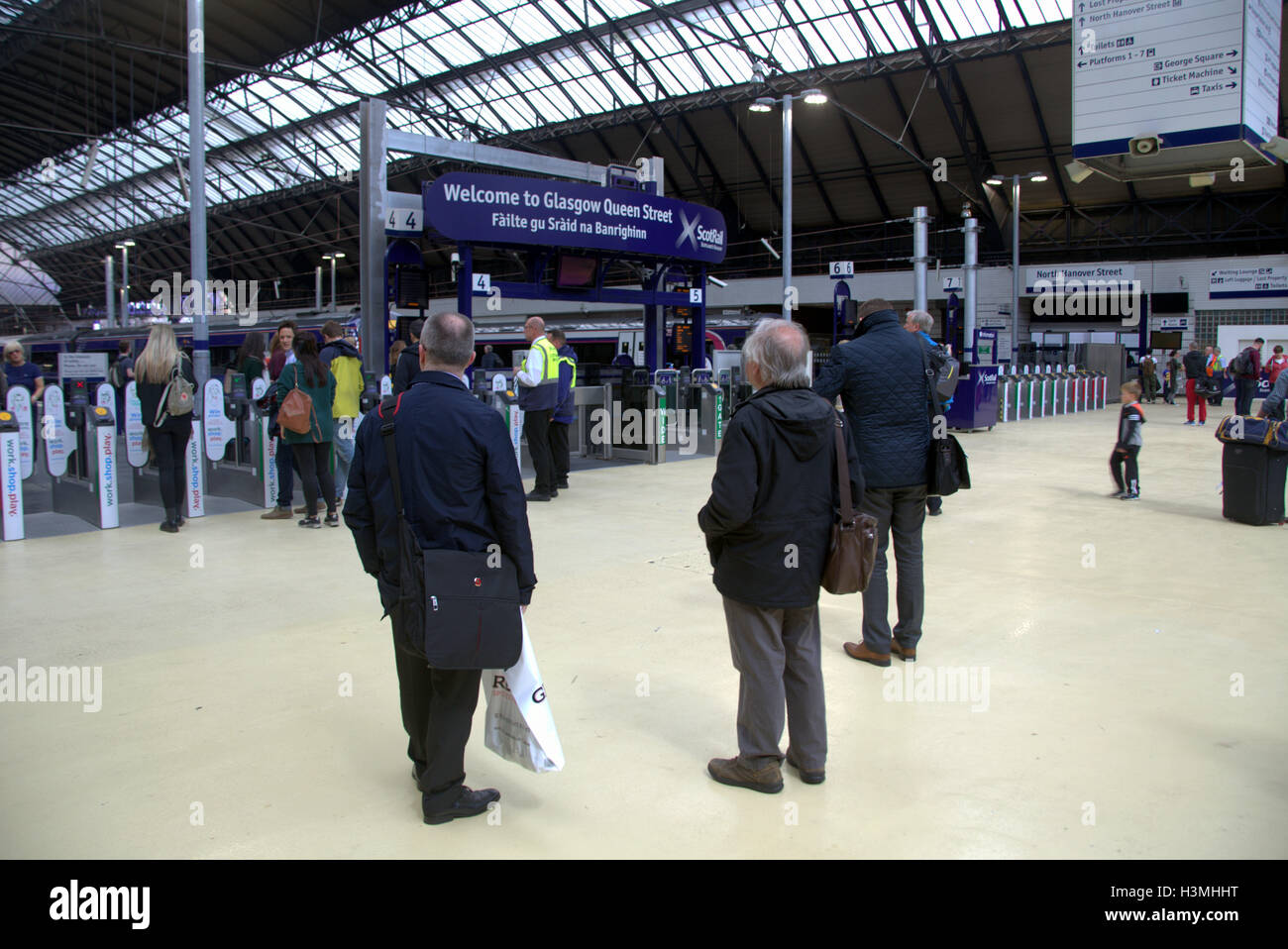 Touristiques de Glasgow en déplacement de train scène avec station de traduction gaélique Banque D'Images