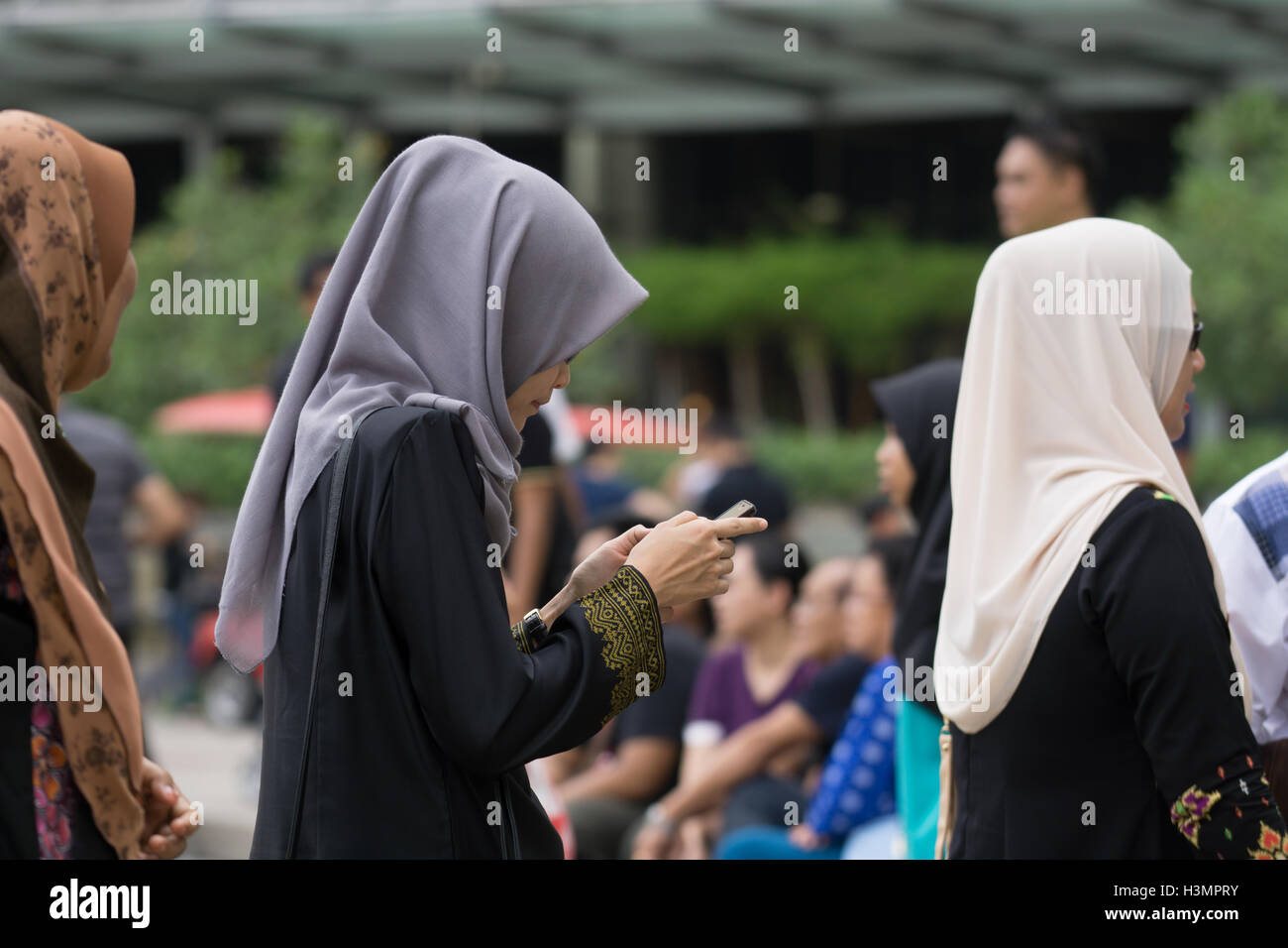 Les femmes musulmanes portant le hijab et l'utilisation d'un téléphone mobile à proximité des Tours Jumelles Petronas à Kuala Lumpur en Malaisie,, Banque D'Images