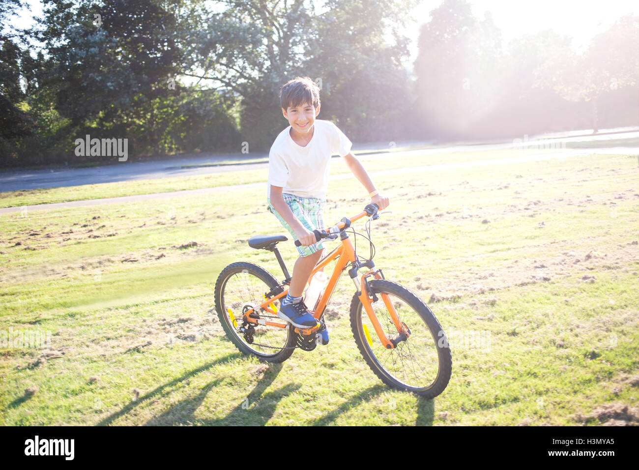 Young boy riding bike dans soleil de l'été Banque D'Images