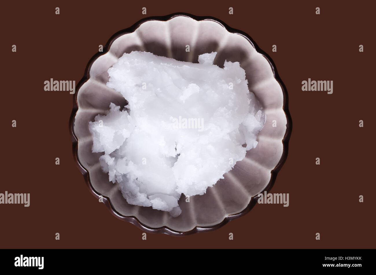 L'huile de noix de coco dans la porcelaine bol sur brown. Extra vierge biologique huile de copra, huile comestible, extrait de viande de coco. Banque D'Images