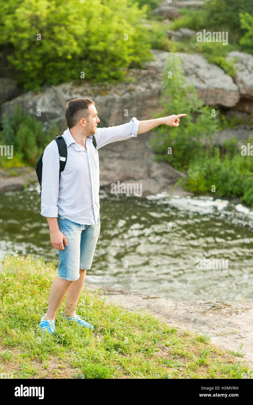 Tourist près d'un fleuve de montagne pouce pointant dans la distance. Banque D'Images