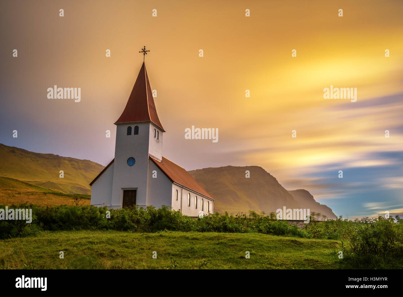 Lever du soleil sur l'église luthérienne au sommet d'une montagne dans la ville de Vik en Islande. Longue exposition. Banque D'Images