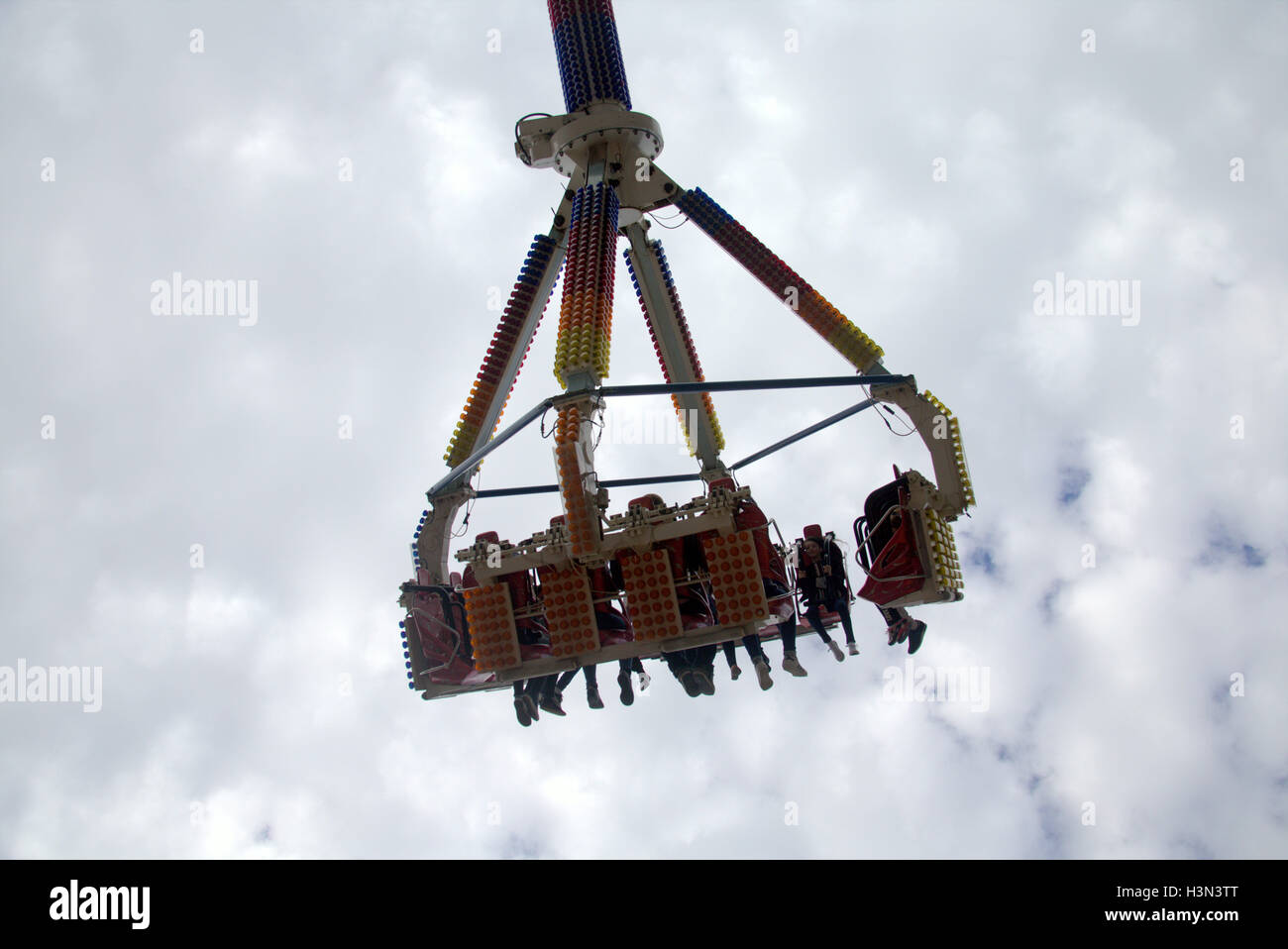 Parc d'ride avec les gens les garçons et les filles d'être levé et tourné sur un bras d'une promenade dans le ciel avec fond de nuage Banque D'Images