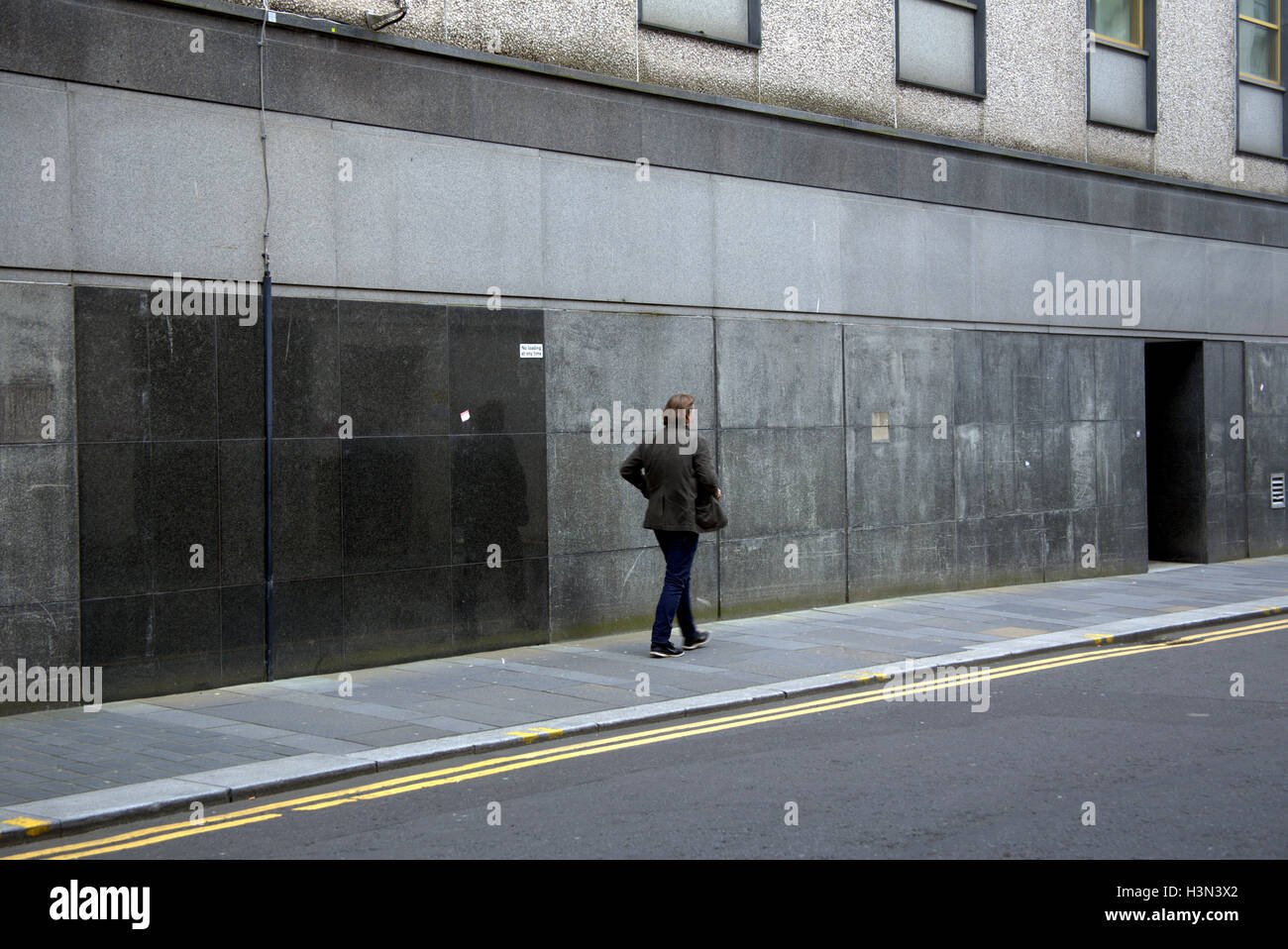 Scènes de rue de glasgow man walking alone fond granit gris Banque D'Images