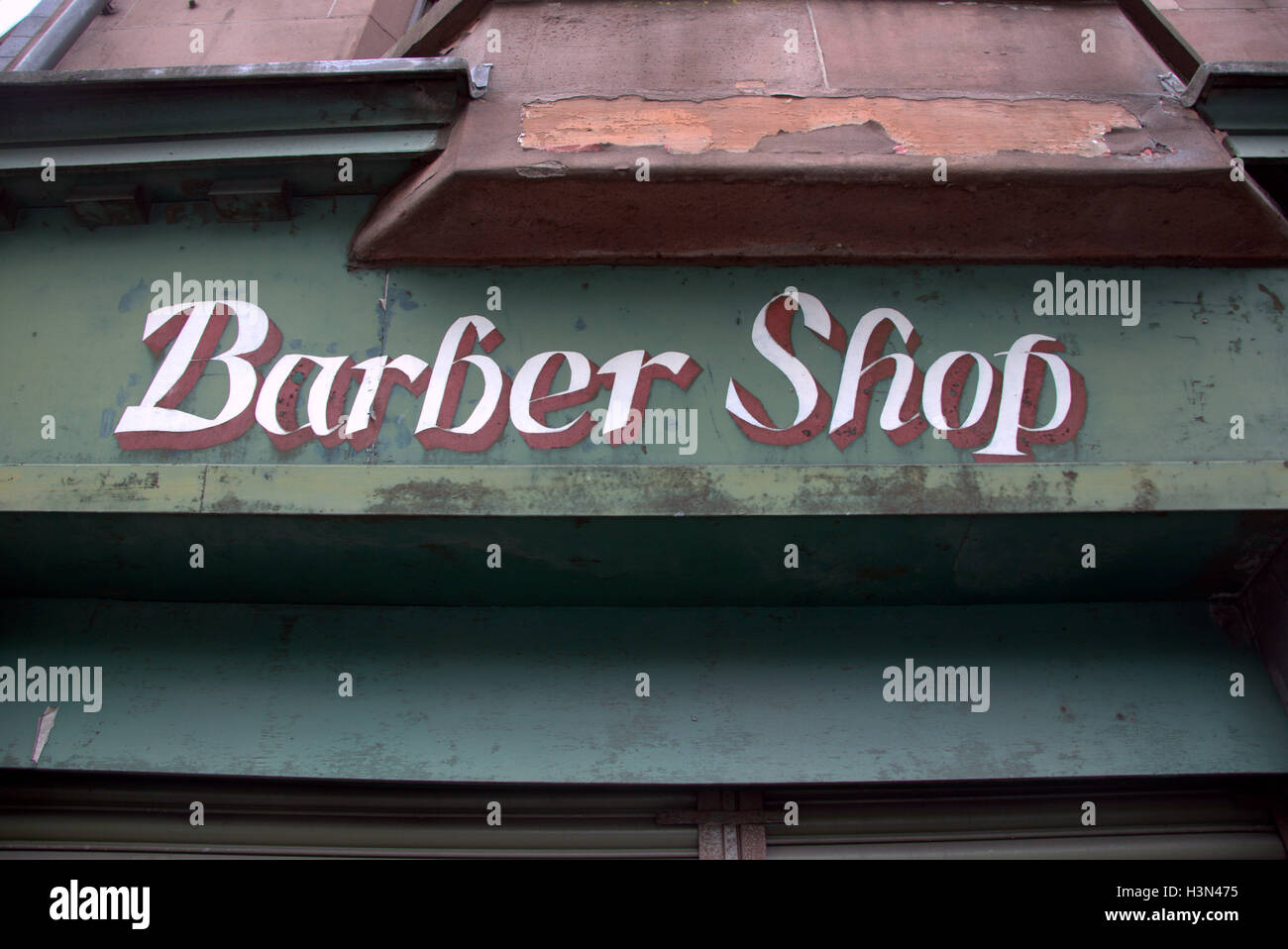 Ancien patiné vert coiffure boutique sign sur bâtiment en grès rouge Banque D'Images