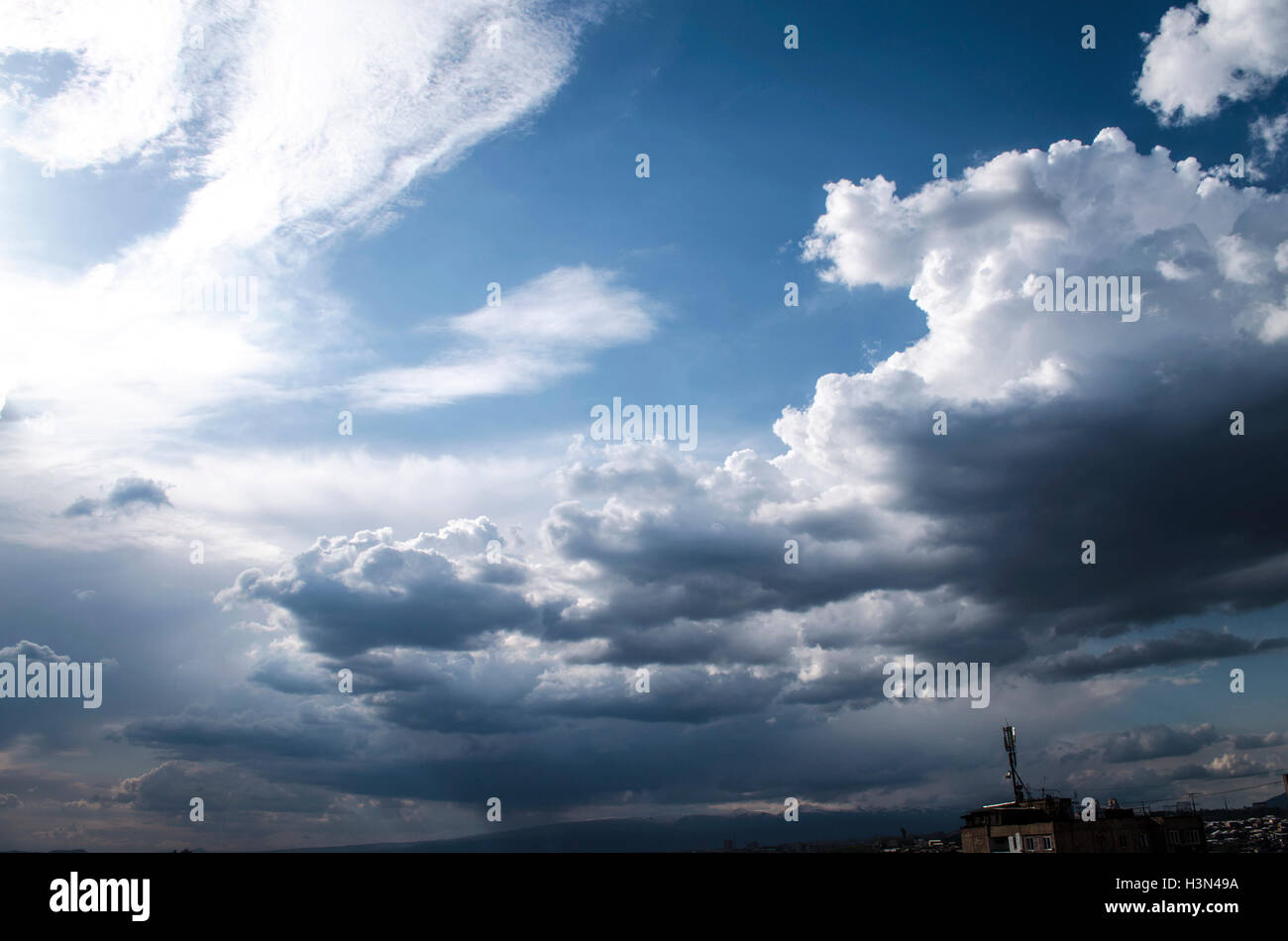 Les nuages orageux dans un milieu d'une journée ensoleillée de printemps sur la ville Banque D'Images
