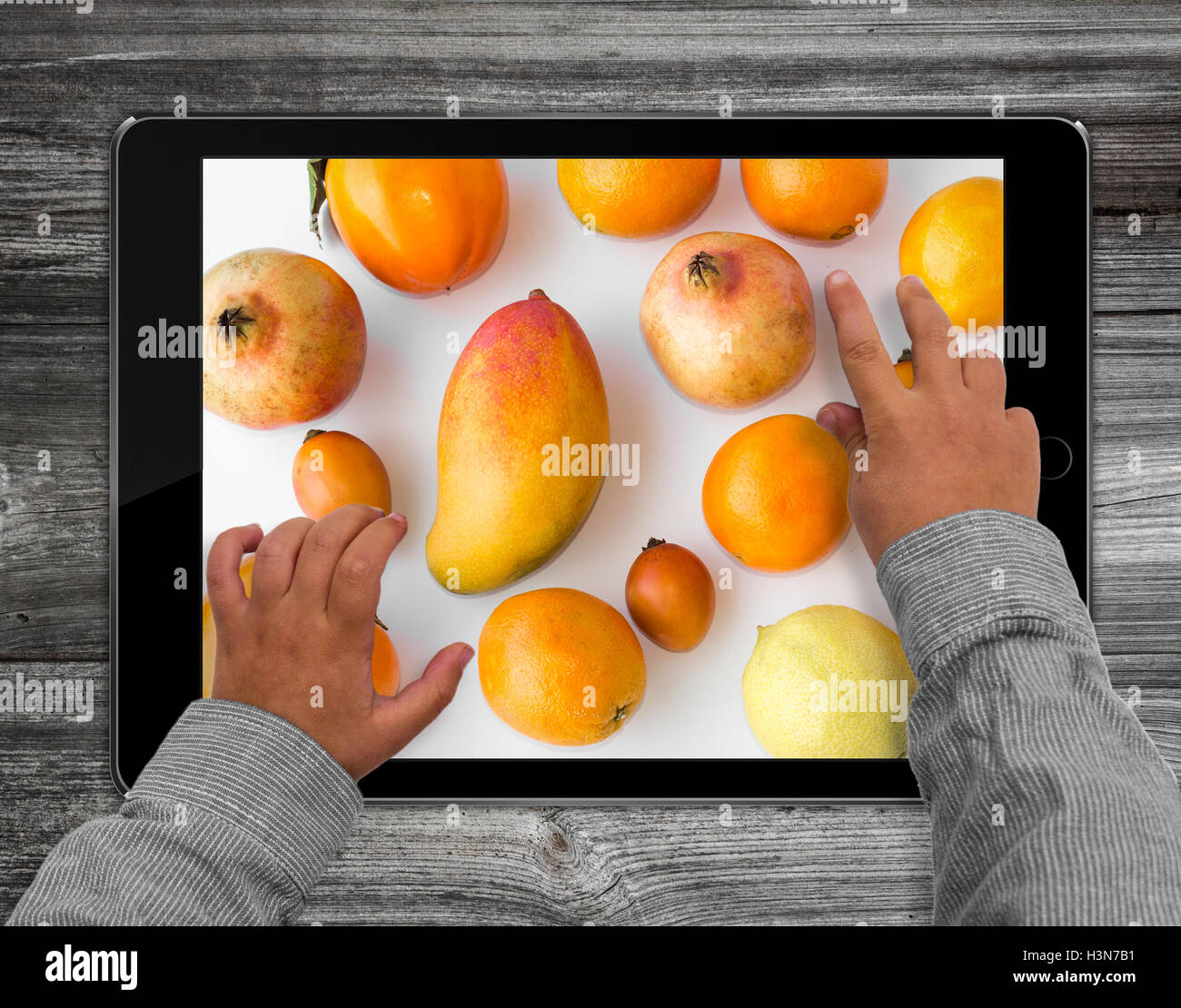 Les mains de l'enfant sur l'ordinateur tablette avec fruits photo Banque D'Images