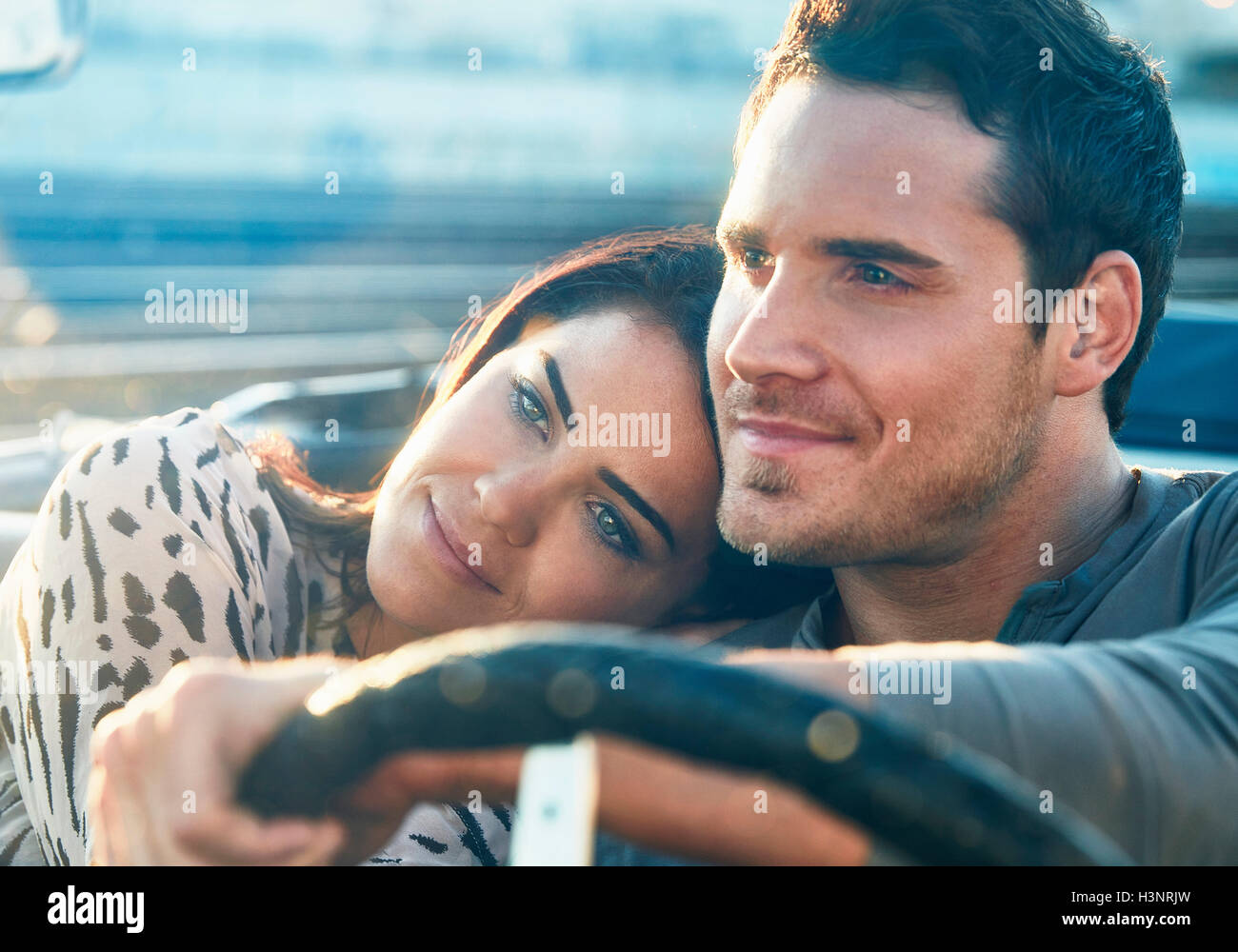 Couple sitting in convertible voiture, regardant le coucher du soleil Banque D'Images