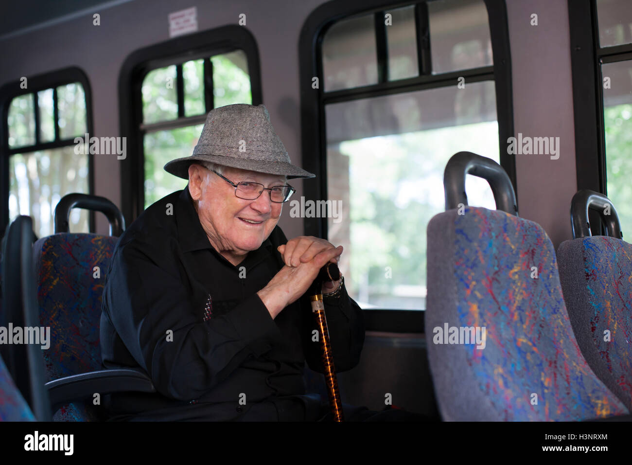 Portrait of senior man sitting on train, holding bâton de marche Banque D'Images