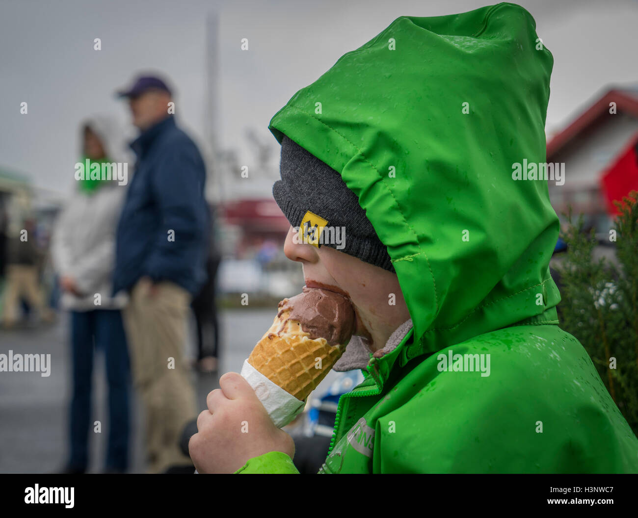 Jeune garçon de manger un cornet de crème glacée au chocolat, jour de pluie, Reykjavik, Islande Banque D'Images