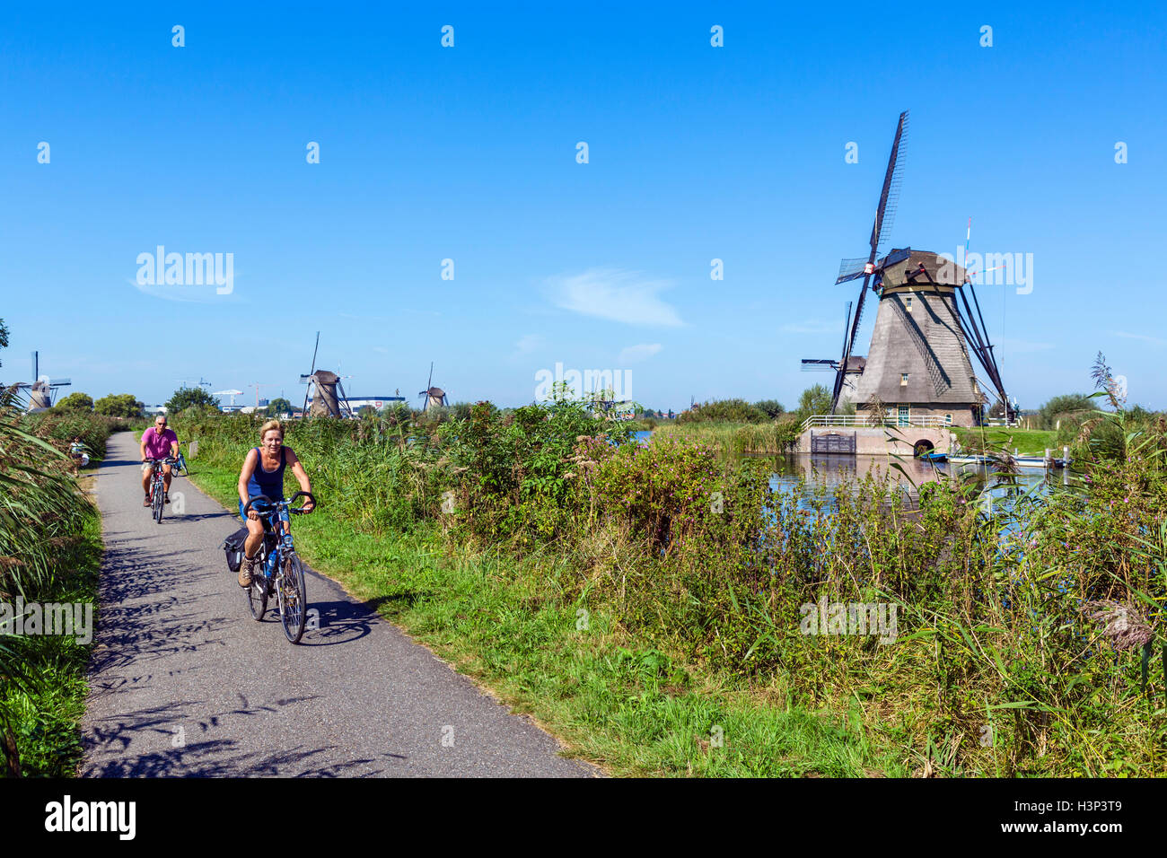 Les cyclistes par les moulins à vent historiques à Kinderdijk, Molenwaard, près de Rotterdam, Pays-Bas Banque D'Images