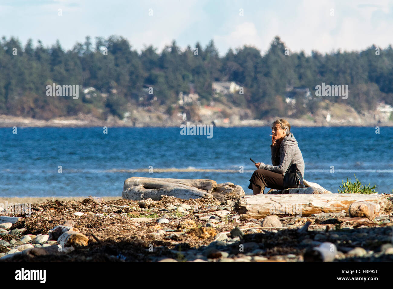 Femme fumant sur la plage - Parc provincial de Rathtrevor Beach - Parksville, île de Vancouver, Colombie-Britannique, Canada Banque D'Images