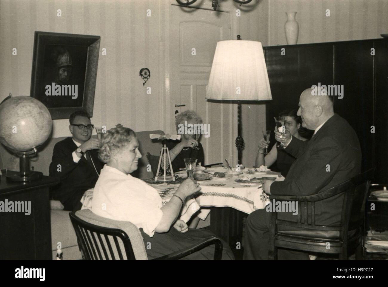 Allemagne - circa 1960 : groupe de trois femmes âgées et deux hommes en costume assis à table de fête dans les mains qu'ils détiennent leurs verres avec de l'alcool Banque D'Images