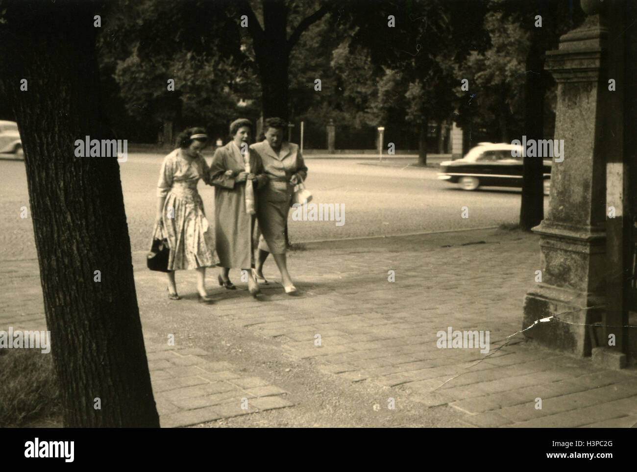Allemagne - circa 1950 : Trois femmes descendre le trottoir sur l'arrière-plan de voitures passant et arbres Banque D'Images